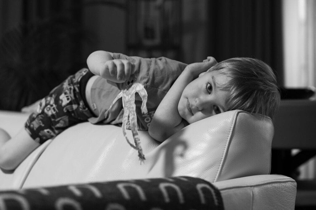Black and white portrait of a young boy on a coach.