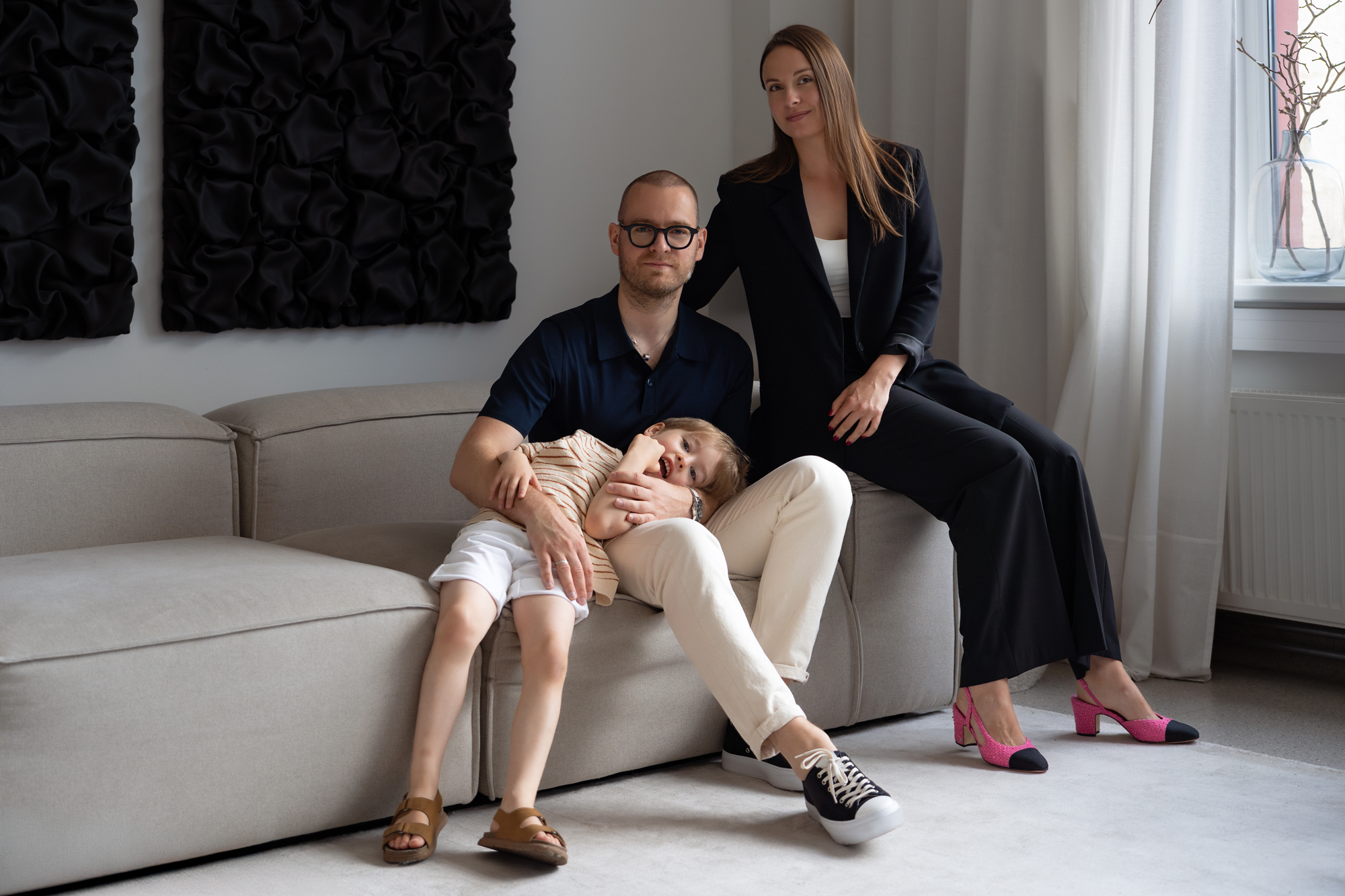 Bright family portrait of parents with child on a modern sofa in a stylish living room