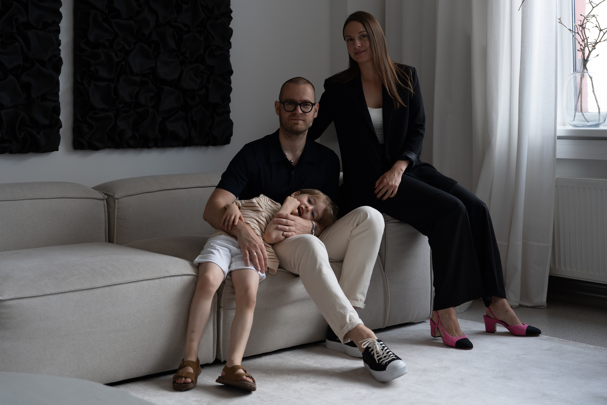 Family portrait in a modern living room with parents sitting on a sofa and child resting on father’s lap