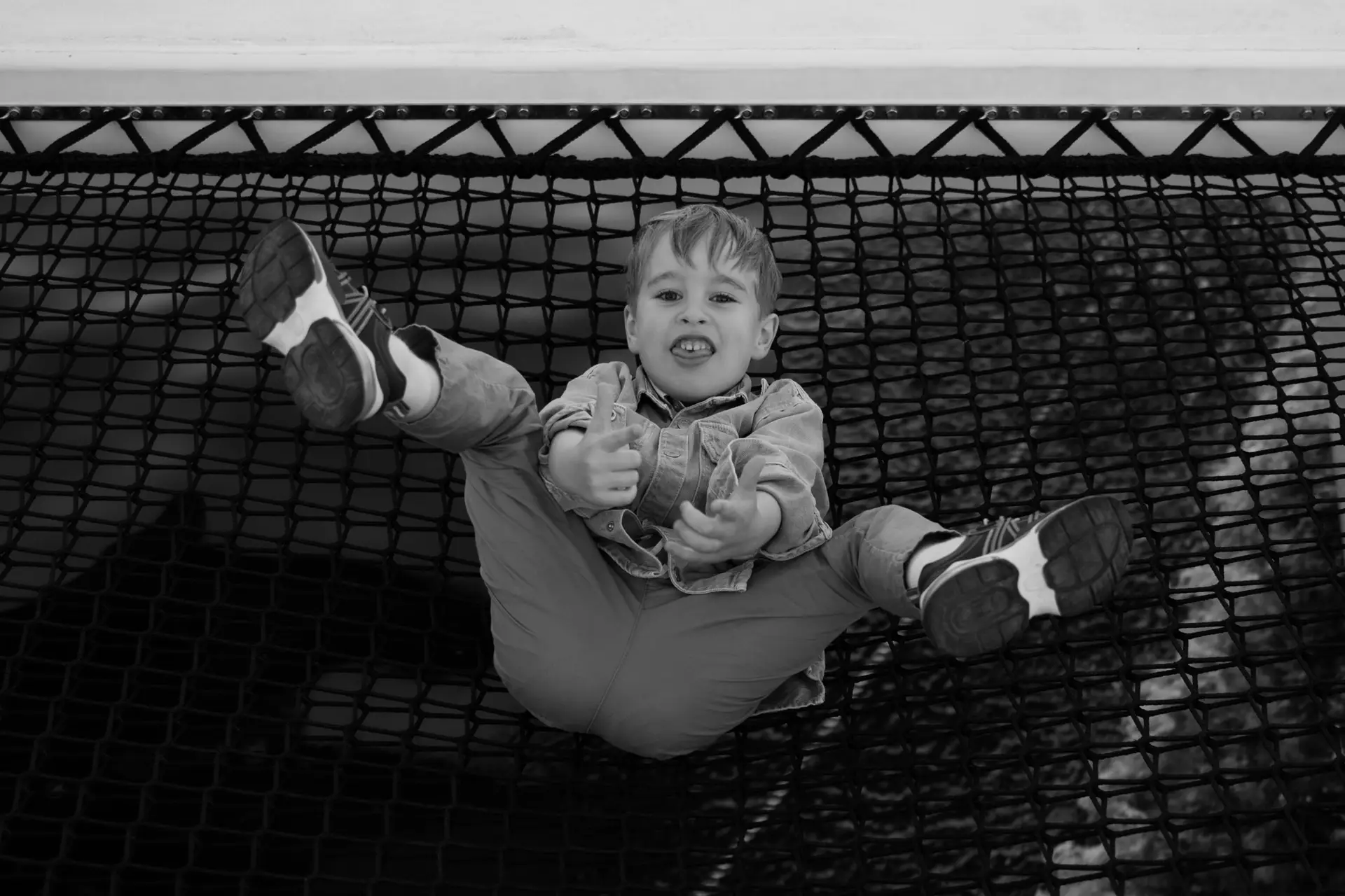 Young boy making a funny face while lying on a net hammock during a family vacation adventure.