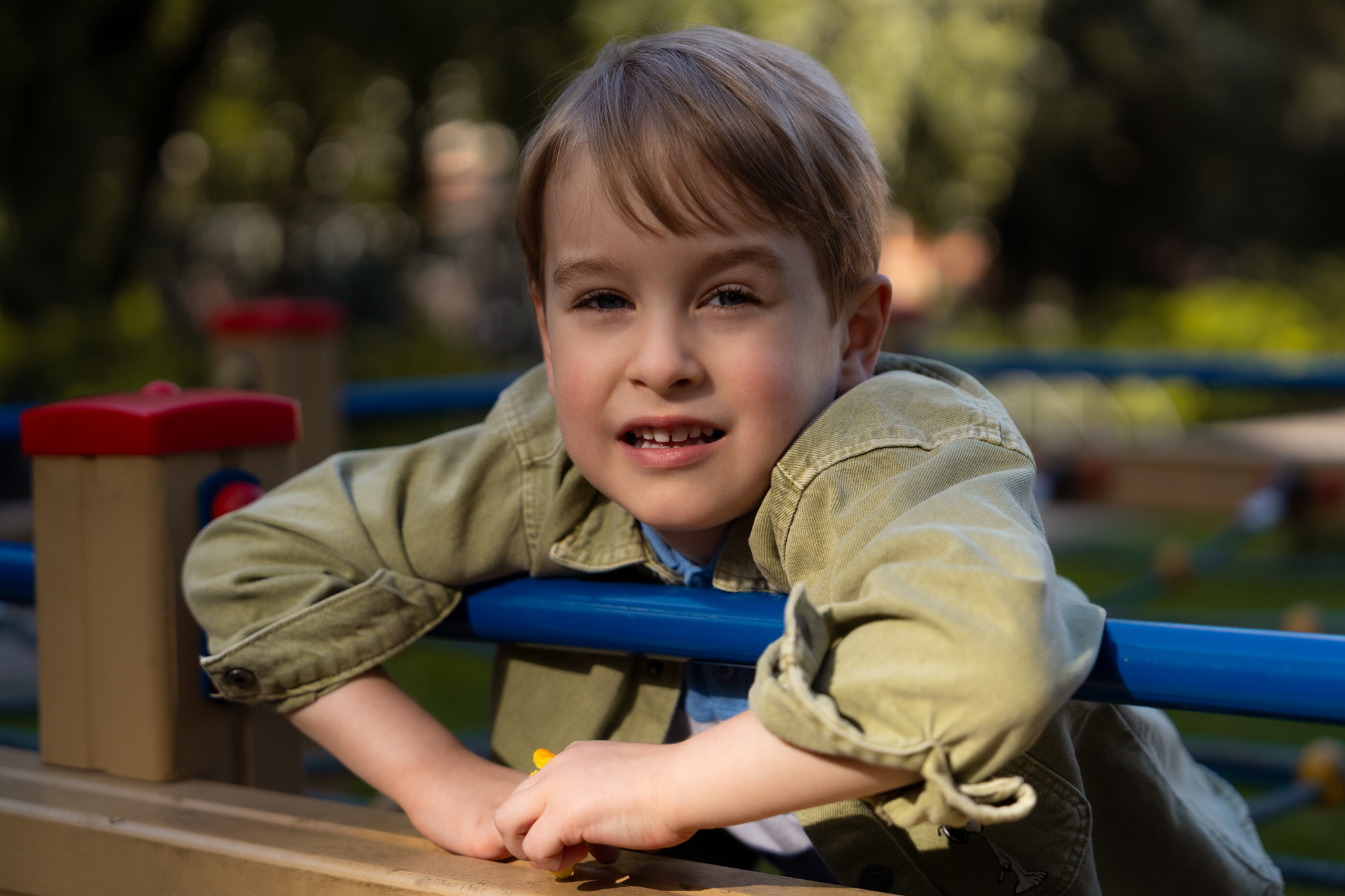 Close-up portrait of a young boy smiling at a playground in natural light